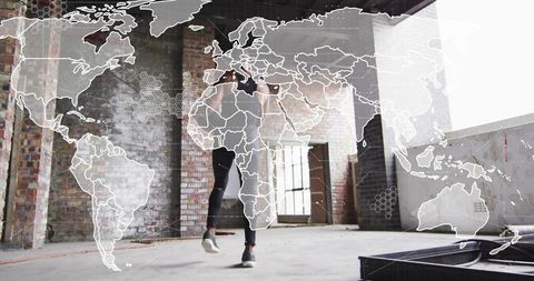 Man jumping midair in industrial loft with world map overlay, urban fitness training