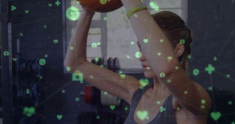 Holding medicine ball overhead while training with digital fitness network overlay