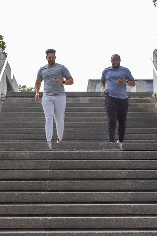 African american men doing stair workout on urban steps wearing fitness trackers