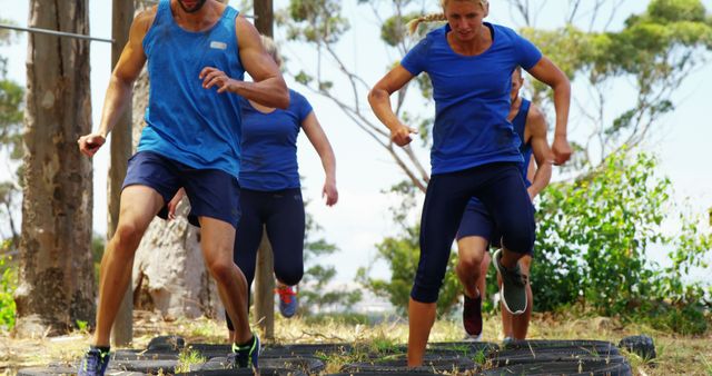 Group navigating through outdoor obstacle course involves teamwork and physical fitness, suitable for portraying teamwork, fitness training, outdoor activities, and group exercises. Ideal for marketing fitness programs, team-building events, health, and wellness promotions.