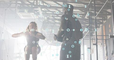 Female athlete jumping in industrial gym, coach monitoring via mobile with data overlay