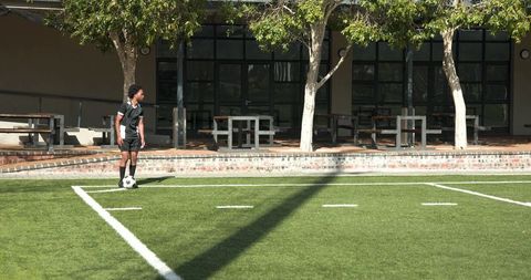 Teen soccer player practicing ball control on school field