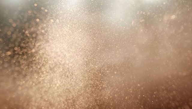 Golden dust and mist drifting in warm backlight with soft bokeh and glowing haze