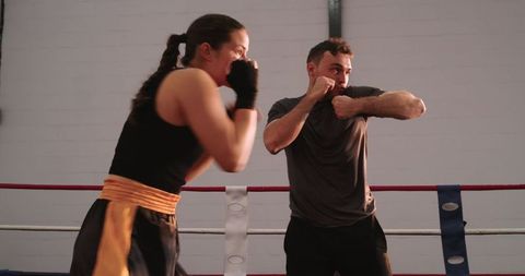 Male and female boxers sparring in ring during intense gym training and skill practice