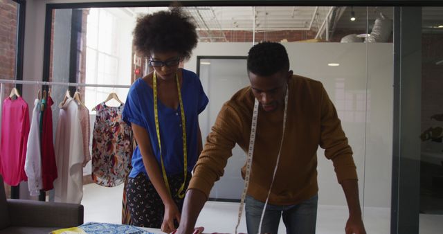 African american male and female fashion designers taking measurements of clothing. independent creative design business.