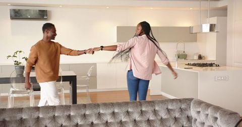Playful couple dancing in modern open-plan kitchen