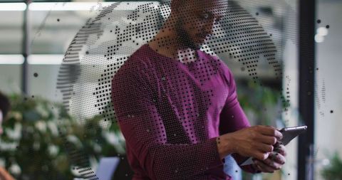 Standing professional holding tablet behind dotted world-map glass in modern workspace