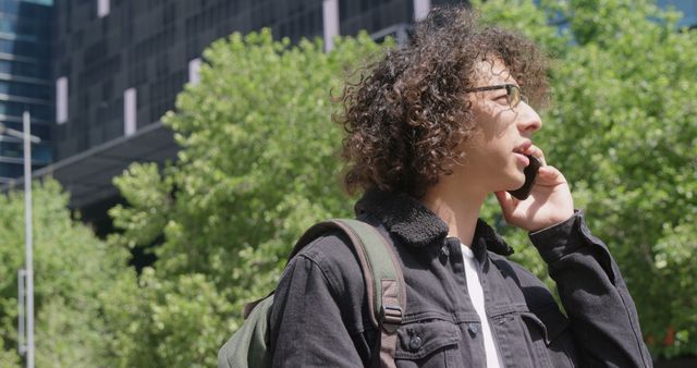 Young Man with Curly Hair Talking on Phone Outdoors in Urban Environment - Download Free Stock Images Pikwizard.com