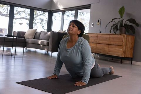 Senior Indian Woman Practicing Yoga in Minimalistic Living Room