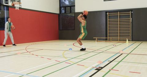 Basketball Coach Observing Player Practicing Shots in Gym