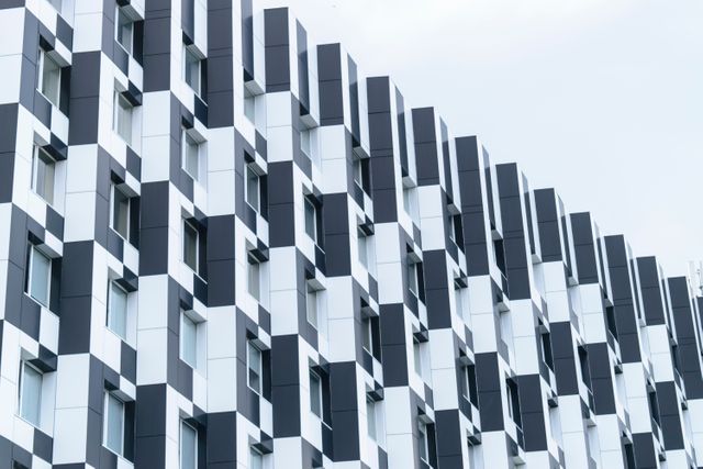 Geometric modern building facade featuring a striking black and white pattern with repeating windows. Ideal for use in articles about urban architecture, modern building design, or contemporary cityscapes.