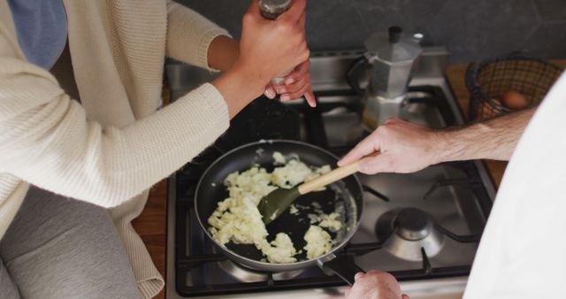 High angle image of happy diverse couple laughing and cooking scrambled eggs in kitchen. Happiness, inclusivity, free time, togetherness and domestic life.