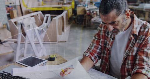 Senior craftsman studying financial graphs in carpentry workshop