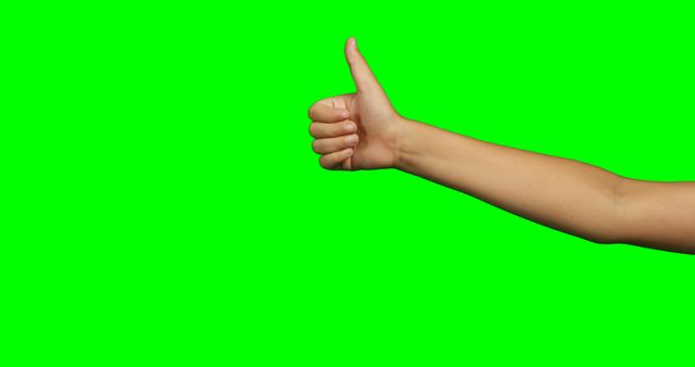 Close-up of person making hand gesture of thumbs up against green screen background