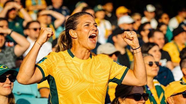 Female football fan cheering passionately in yellow green jersey, stadium crowd celebration