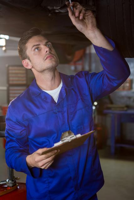 Attentive mechanic examining car at repair garage