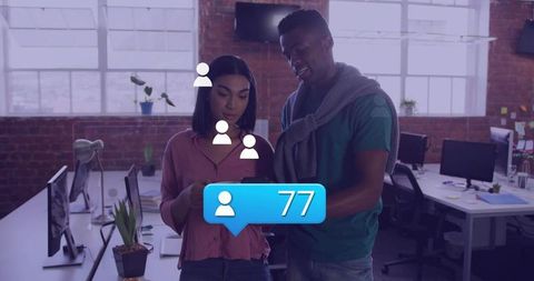 Coworkers collaborating over smartphone showing 77 followers notification in open-plan office