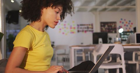 Young Woman Working on Laptop in Creative Office Space