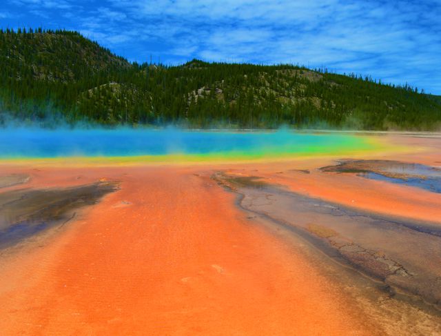 Geothermal pool displaying vibrant rainbow colors, located in Yellowstone National Park. Minerals and heat create stunning multicolored bands, making the landscape uniquely captivating. Ideal for use in travel, nature, and educational content related to natural wonders and geology.