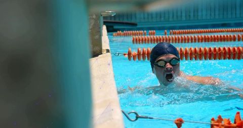 Competitive swimmer taking breath during front crawl at pool edge, orange dividers