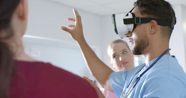 Medical professional wearing VR headset, interacting in simulated environment, observed by colleague. Useful for content on medical training, healthcare innovations, virtual reality applications in medicine, and hospital education technologies.