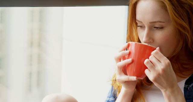 Redheaded Woman Sipping Hot Beverage by Window - Download Free Stock Images Pikwizard.com