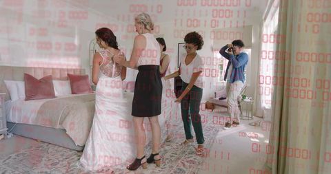 Bridal party adjusting lace gown while photographer capturing candid getting-ready moment