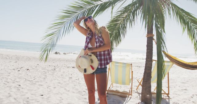 Happy caucasian woman smiling and holding hat on beach. Lifestyle, realxation, nature, free time and vacation.