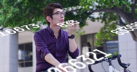 Asian man speaking into smartphone while biking in city plaza with numeric overlays