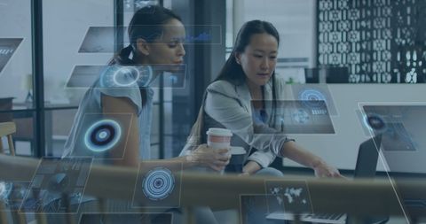 Businesswomen analyzing data projections in modern office