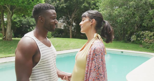 Happy diverse couple holding hands at swimming pool in garden - Download Free Stock Photos Pikwizard.com