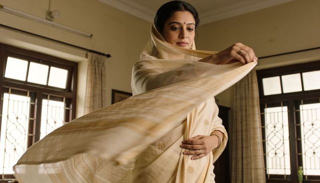 Indian woman draping cream sari pallu with delicate embroidery in sunlit classic interior