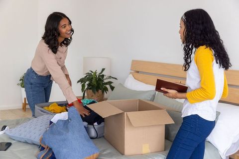Two friends organizing clothes at home with joyful interaction