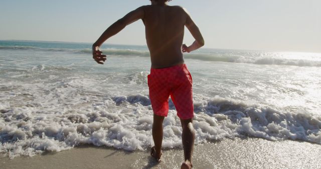 Man Running into Ocean Waves at Sunny Beach - Download Free Stock Images Pikwizard.com