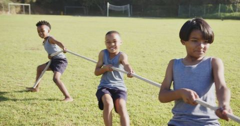 Smiling Boys Enjoying Tug-of-War Games on Sunny Field
