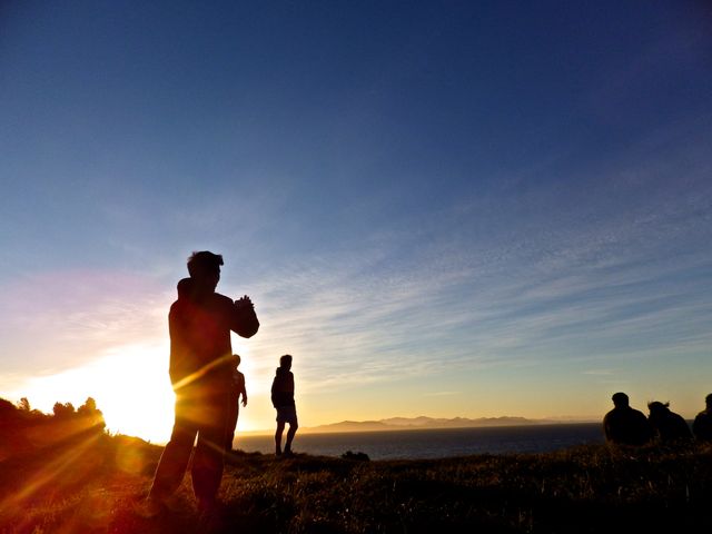 People silhouetted against a stunning sunset, capturing the beautiful landscape from a mountain or elevated area. Great for use in travel blogs, nature websites, relaxation content, and anything promoting outdoor activities or peaceful scenic views.
