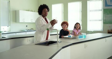 African american teacher conducting hands-on science experiment with two students in lab