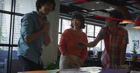 Creative team celebrating breakthrough during casual coworking session in modern office