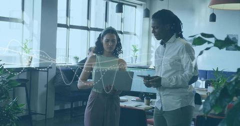 Coworkers Collaborating in Modern Office with Digital Data Overlay