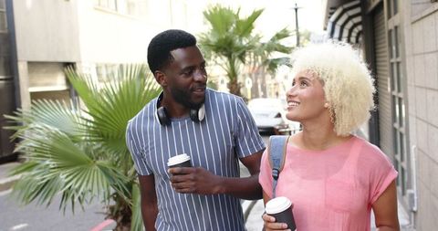 Happy Diverse Couple Exploring City with Coffee in Hand