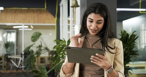 Indian professional woman using tablet in modern coworking office with plants and bicycle