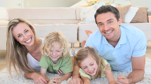 Smiling Family Relaxing Together on Carpet Home