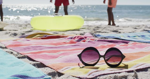 Image of sunglasses, towels and beach equipment lying on beach. Holidays, vacations, relax and beach concept.