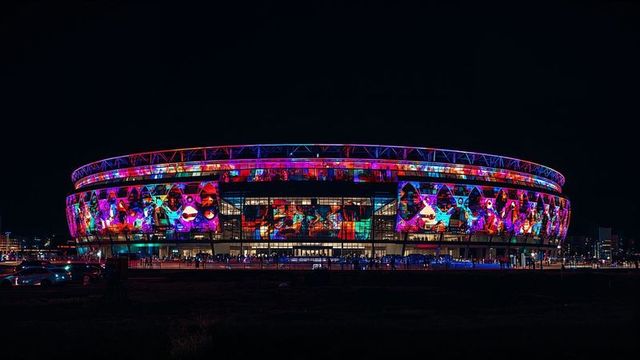 Colourful projection mapping on modern stadium exterior at night