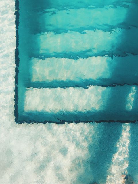 A clear view of underwater steps leading into a clean blue swimming pool. Ideal for use in designs and articles about pool maintenance, summer activities, fitness and relaxation. Perfect for promoting aquatic facilities, travel destinations, and lifestyle blogs.