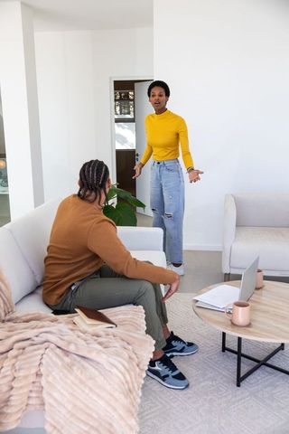 Diverse Couple Discussing in Modern Living Room with Laptop