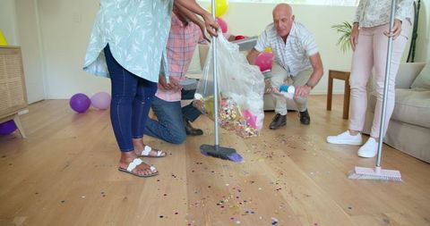 Senior Friends Cleaning Confetti from Floor After Celebration
