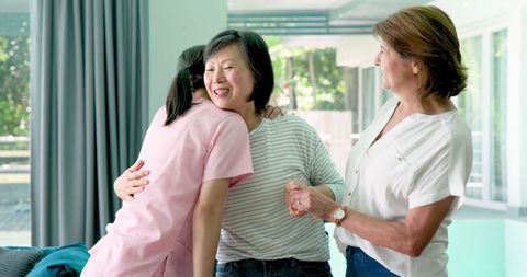 Senior Woman Seated in Wheelchair with Caring Companions at Home