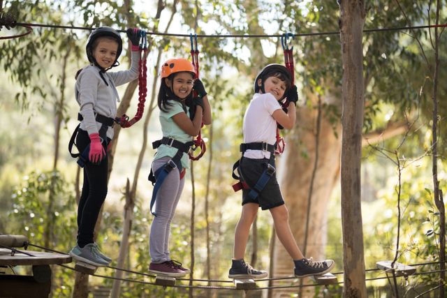 Portrait of happy kids crossing zip line on a sunny day