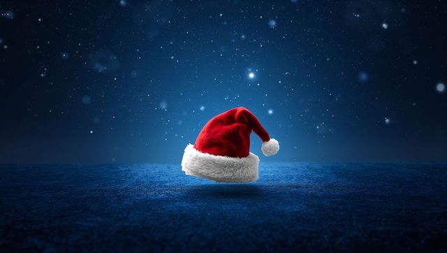 Red Velvet Santa Hat Resting on Starry Blue Floor with Soft Spotlight and Bokeh